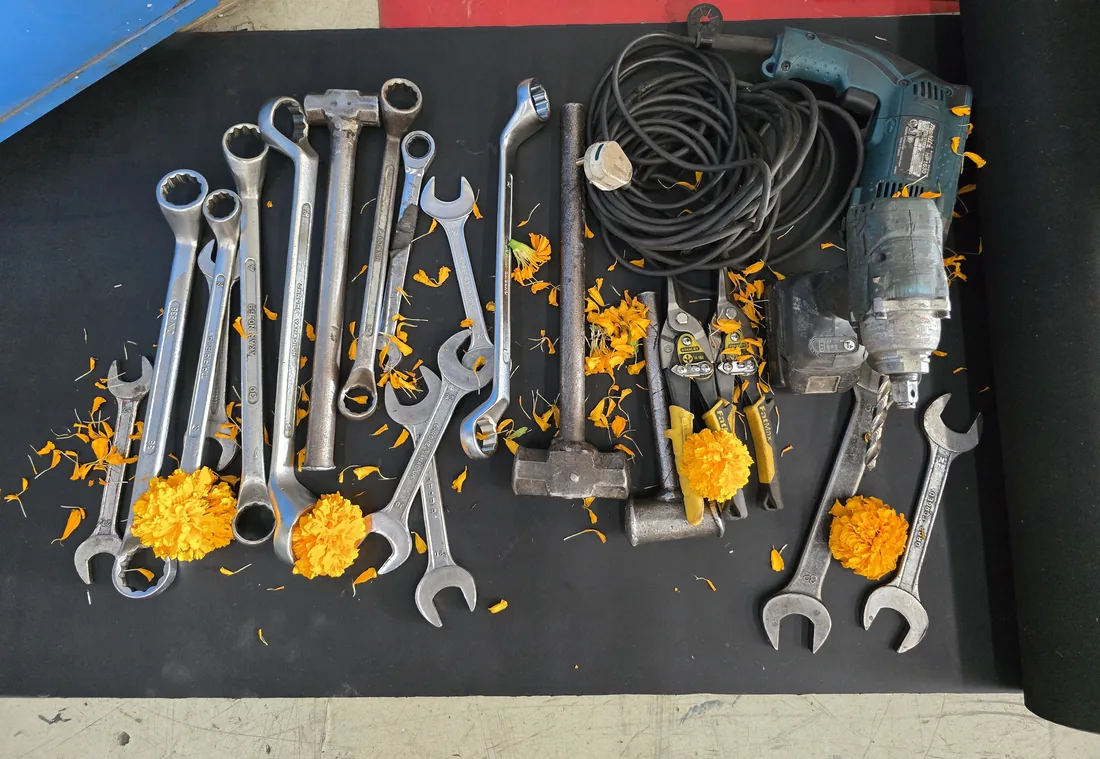 Spanners, a hammer and a drill laid out with marigold flowers for Ayudha Puja