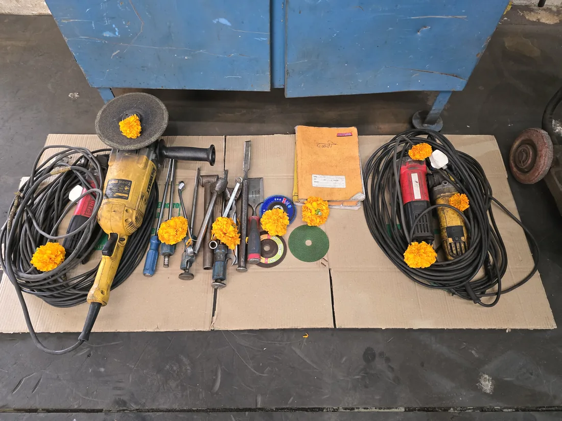 Angle grinders, chisels and cutting discs laid out with marigold flowers for Ayudha Puja