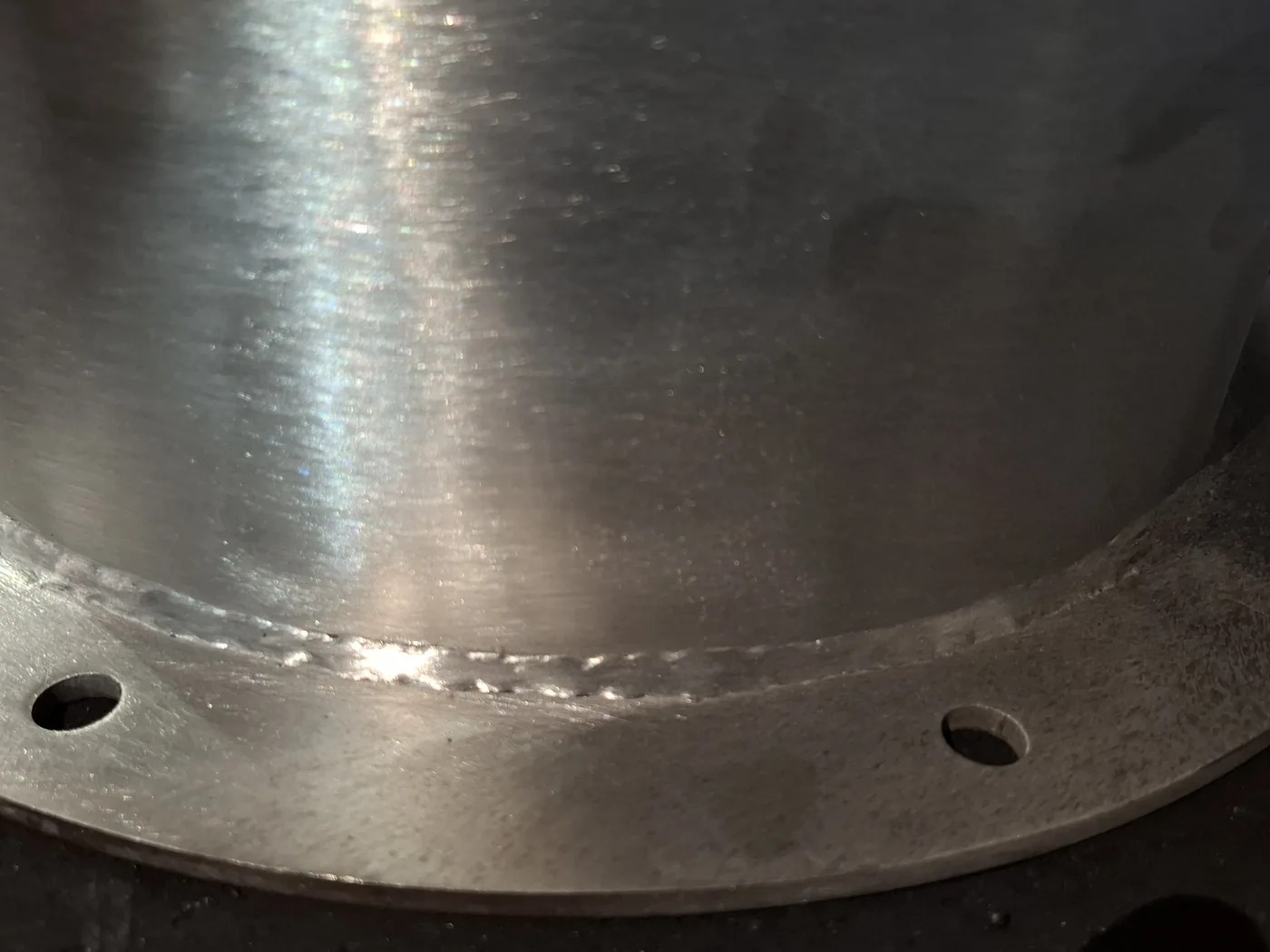 Close-up of a laser-welded circumferential seam joining a stainless shell to its flange